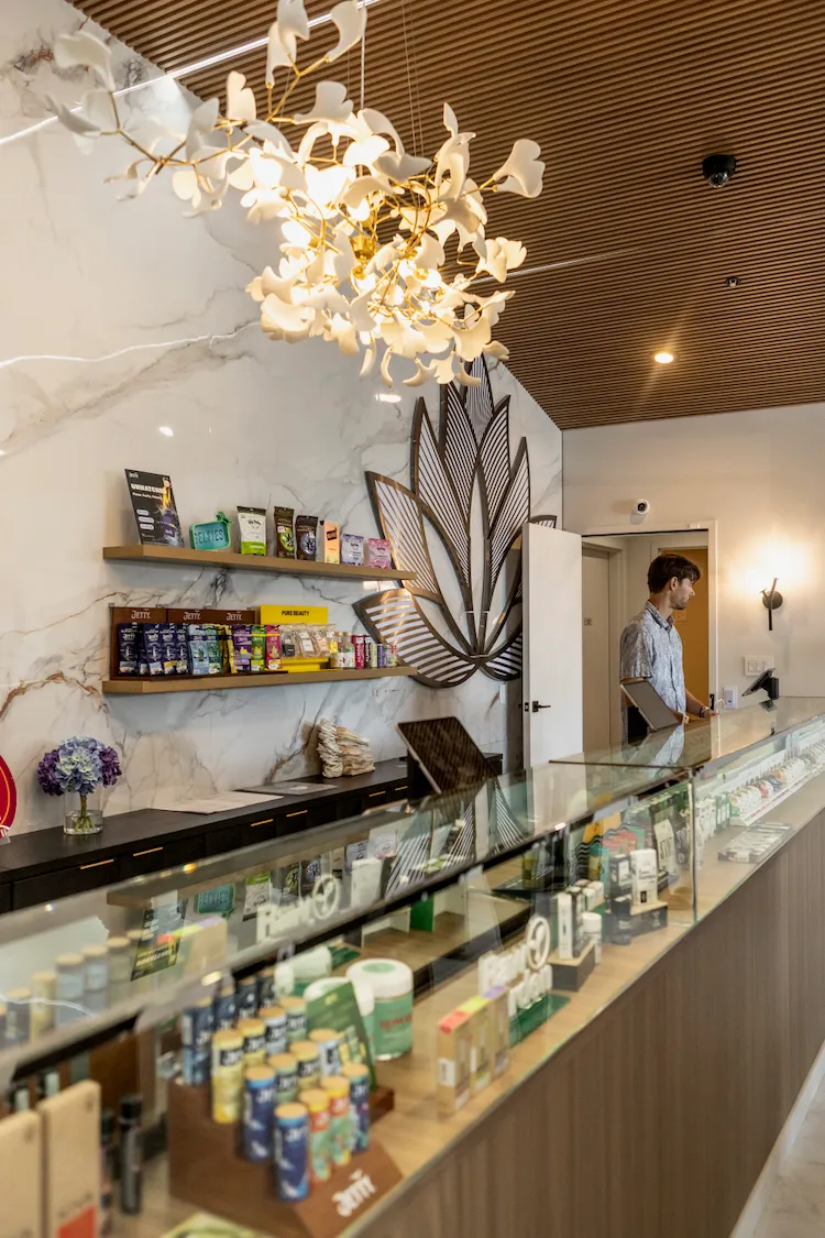 Inside La Flōr in Fairfax: warm wood, the lit retail counter and product cases.